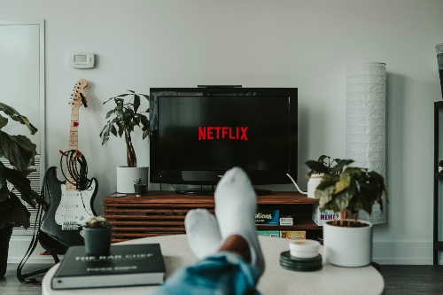 A person watching Netflix A person watches Netflix with their feet up on a coffee table, wearing white socks